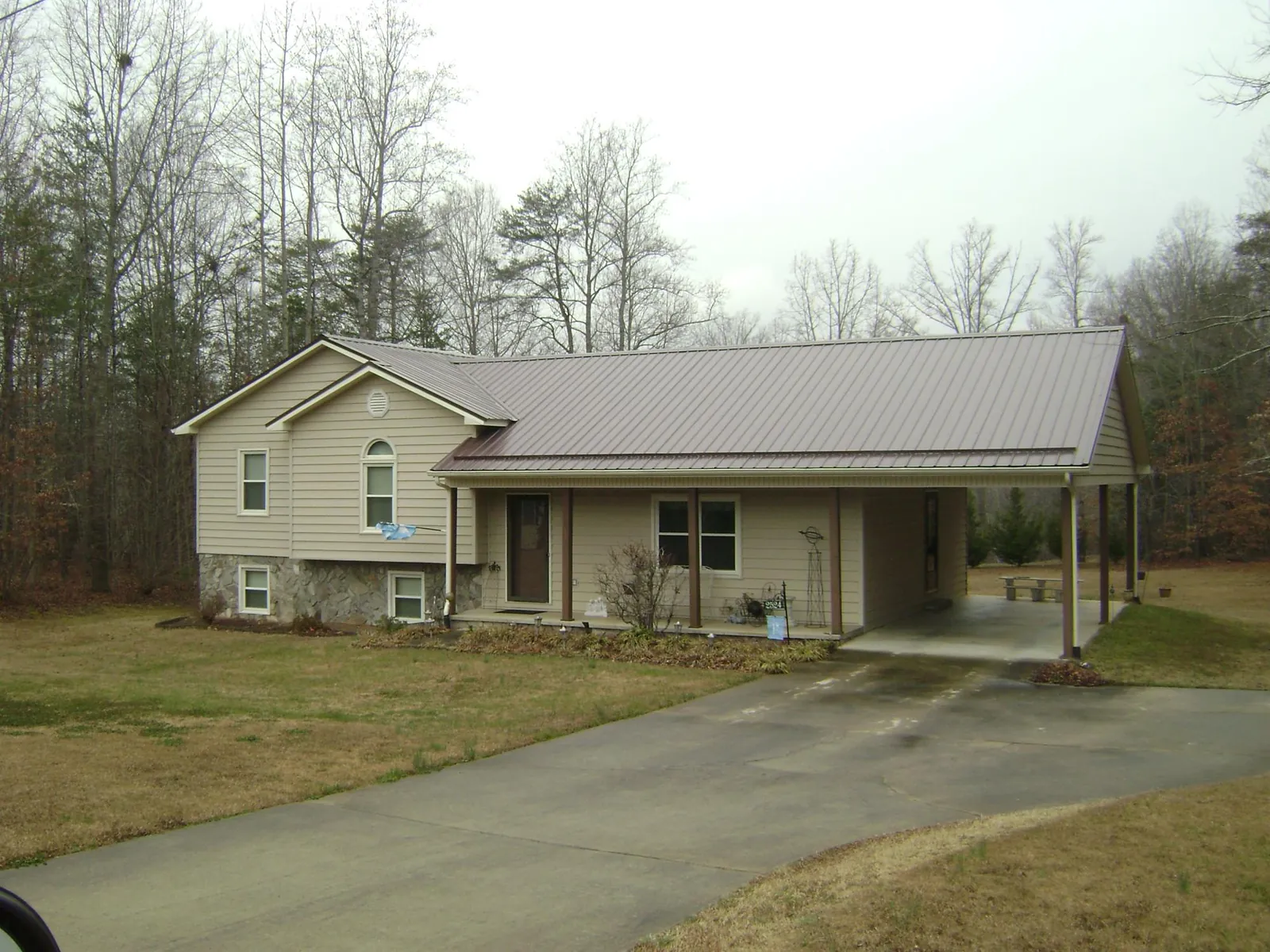 Brown metal roof on a tan split level home with an attached carport in Eagle